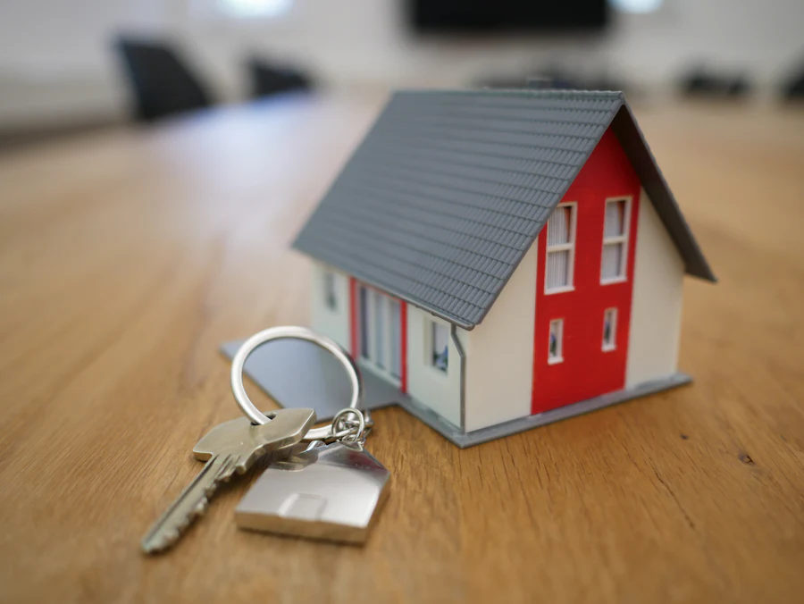 Llaves de casa junto a una maqueta de vivienda sobre una mesa de madera